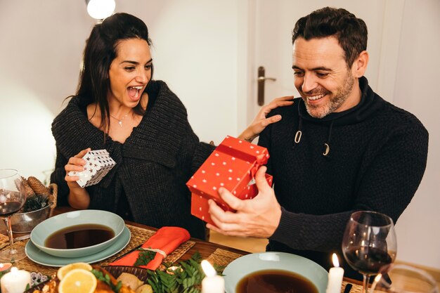 Coppie allegre con i regali alla cena di Natale