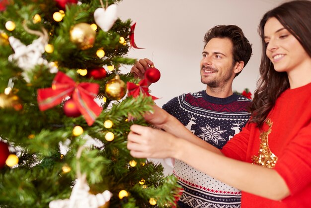 Coppie amorose che appendono le decorazioni sull'albero di Natale