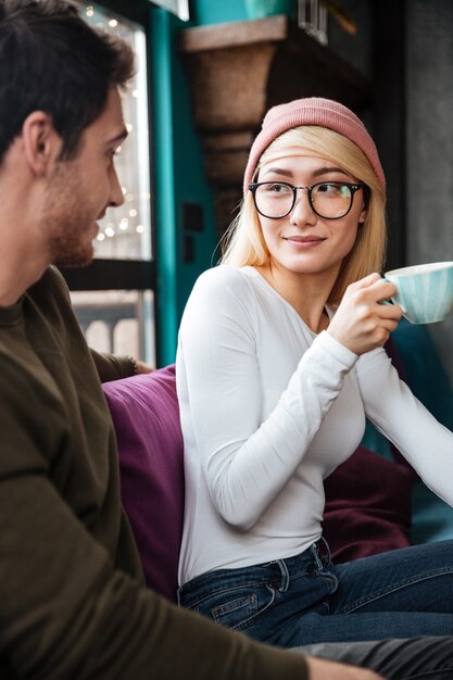 Coppie amorose sorridenti che si siedono in caffè e che bevono caffè