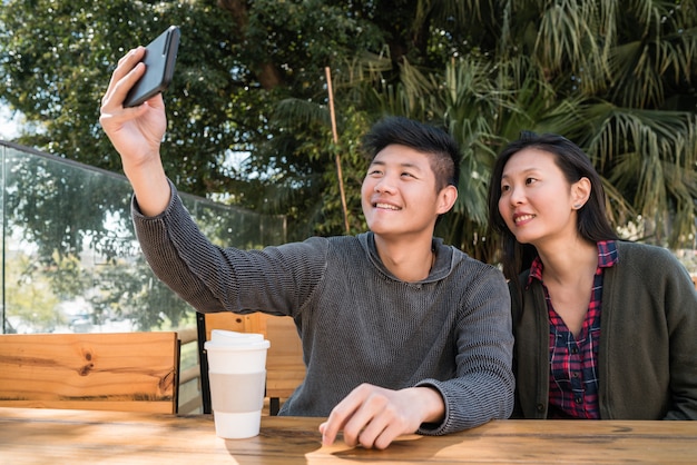 Coppie asiatiche che prendono un selfie con il telefono cellulare.