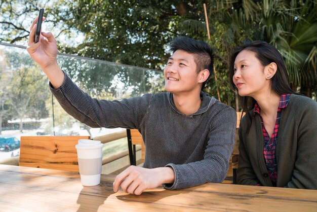 Coppie asiatiche che prendono un selfie con il telefono cellulare.