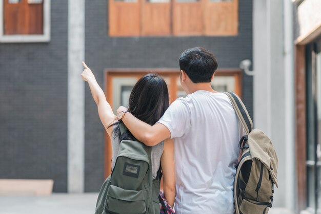 Coppie asiatiche del viaggiatore con zaino e sacco a pelo del viaggiatore che ritengono viaggio felice a Pechino, Cina, coppie allegre del giovane adolescente che camminano a Chinatown.