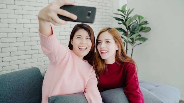 Coppie asiatiche lesbiche che utilizzano selfie dello smartphone in salone a casa