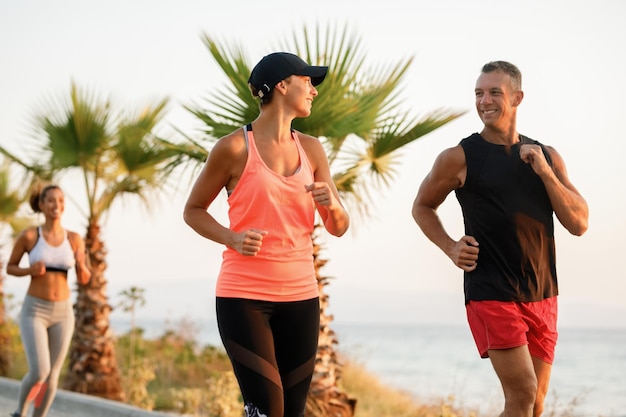 Coppie atletiche felici che parlano tra loro mentre corrono insieme all'aperto.