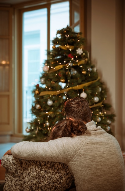 Coppie che abbracciano vicino all&#39;albero di Natale