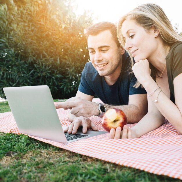 Coppie che esaminano computer portatile sul picnic