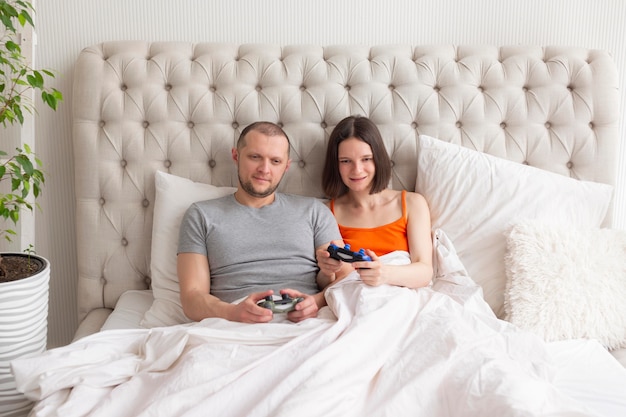 Coppie che giocano ai videogiochi a letto