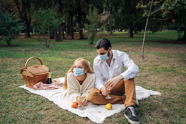 Coppie che hanno un picnic mentre indossano maschere mediche