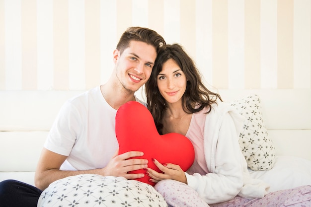 Coppie che posano con il cuore sul letto