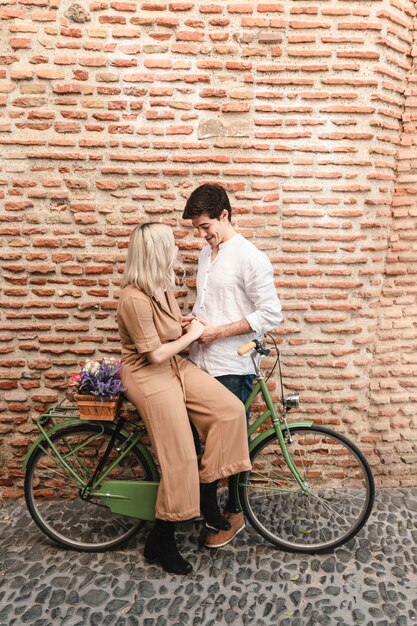 Coppie che posano contro il muro di mattoni con la bicicletta