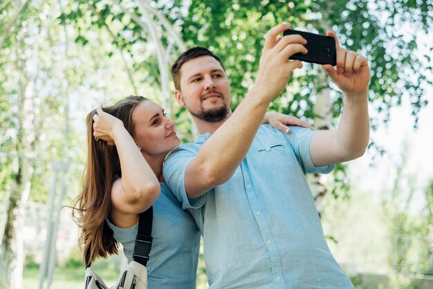 Coppie che prendono selfie nella foresta di betulle