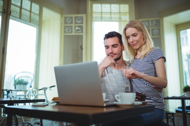 Coppie che si siedono a tavola e con laptop