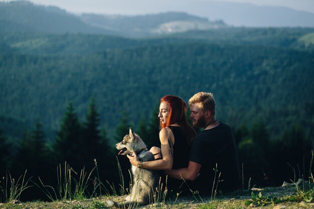 Coppie che si siedono su un campo verde guardare alla natura con il loro cane