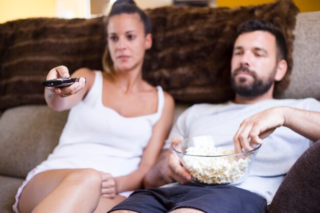 Coppie che si siedono sul sofà con popcorn che guarda televisione