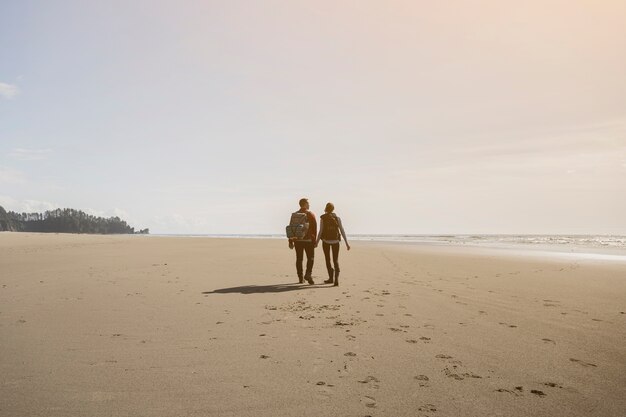Coppie che si tengono per mano e che camminano sulla spiaggia