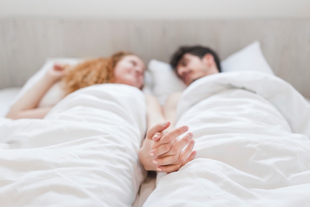 Coppie che si tengono per mano mentre trovandosi sul letto