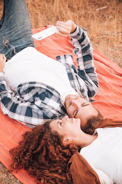 Coppie che si trovano sulla coperta che prende un selfie