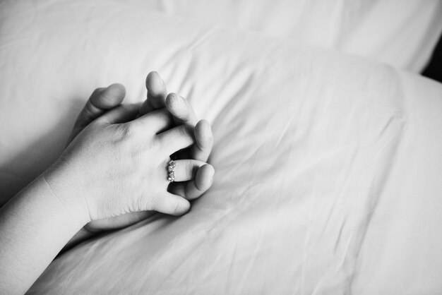 Coppie che tengono le mani sul letto