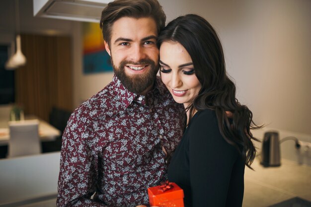 Coppie contenti che posano alla macchina fotografica con il regalo