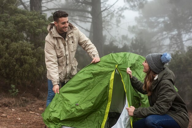 Coppie del colpo medio che mettono su una tenda