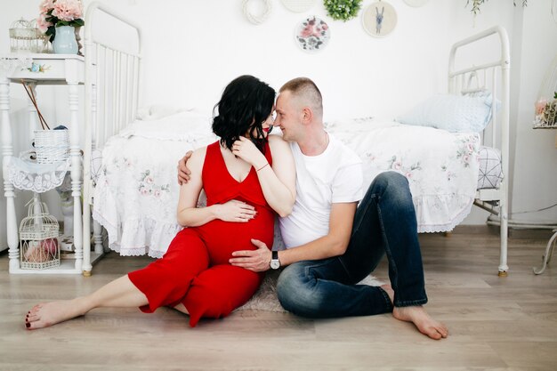 Coppie del marito bello e della donna graziosa pragnant che posano allo studio