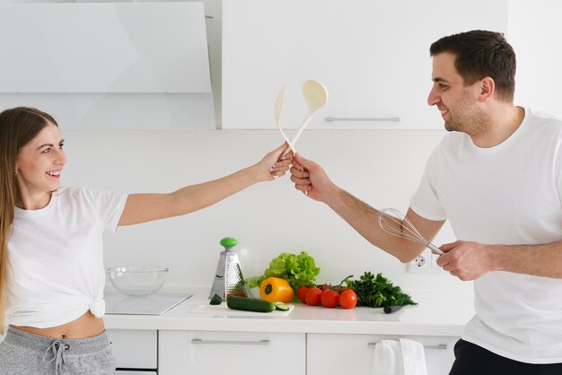 Coppie di vista laterale che giocano mentre cucinando