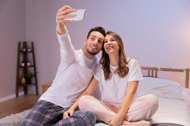 Coppie felici a letto prendendo selfie