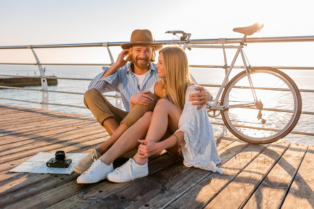 Coppie felici attraenti che viaggiano in estate via mare sulle biciclette, moda stile hipster boho uomo e donna divertendosi insieme