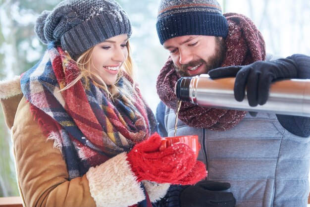 Coppie felici che bevono tè caldo in inverno