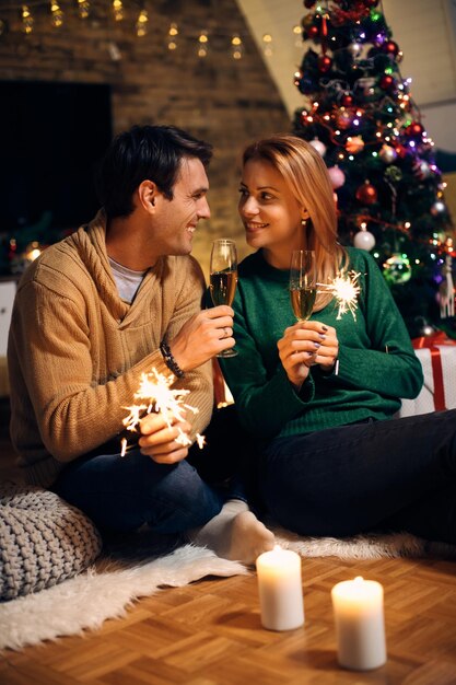 Coppie felici che brindano con Champagne alla vigilia di Natale a casa