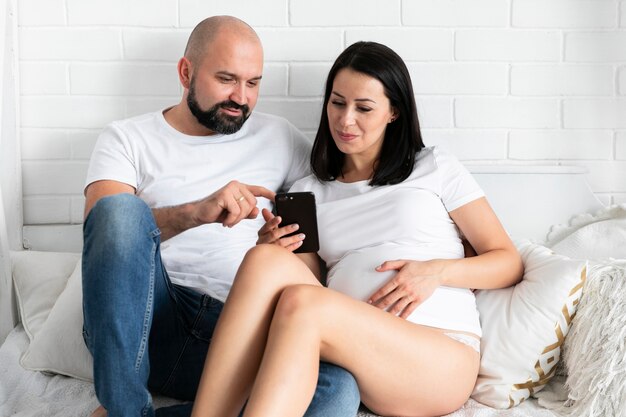 Coppie felici che controllano telefono per i nomi del bambino