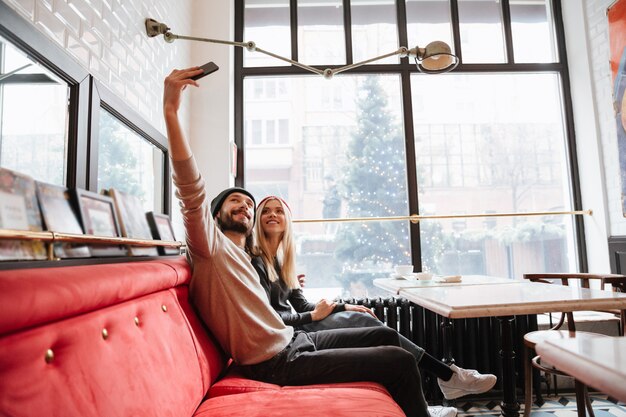 Coppie felici che fanno selfie in caffè