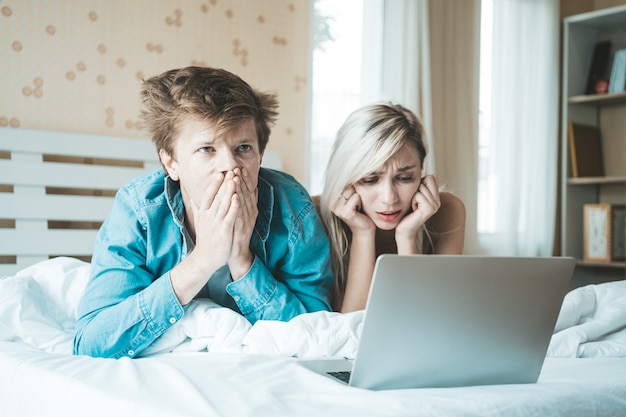 Coppie felici che per mezzo del computer portatile sul letto