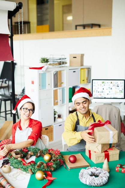 Coppie felici che preparano i regali e le decorazioni di natale