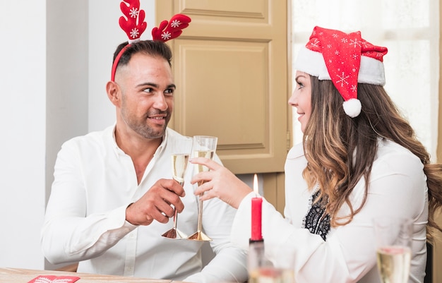 Coppie felici che risuonano i vetri del champagne alla tavola festiva