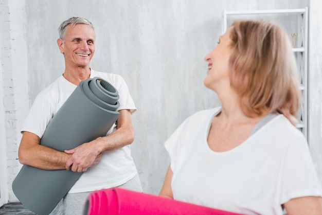 Coppie felici che se lo esaminano che tiene la stuoia di yoga