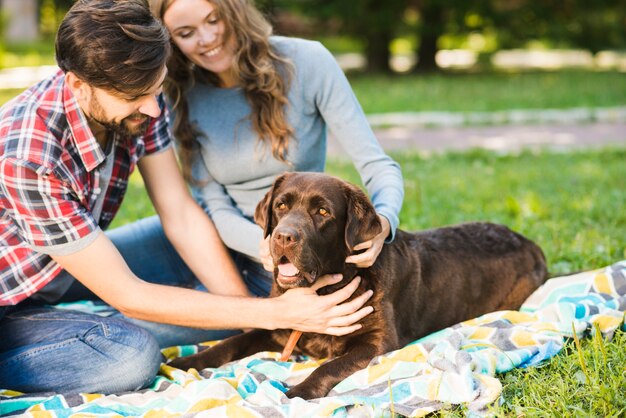 Coppie felici che si siedono con il loro cane in giardino