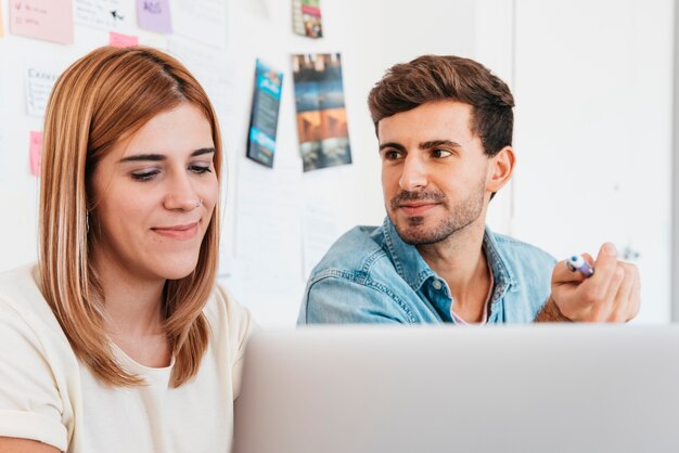 Coppie lavoranti sorridenti che praticano il surfing Internet