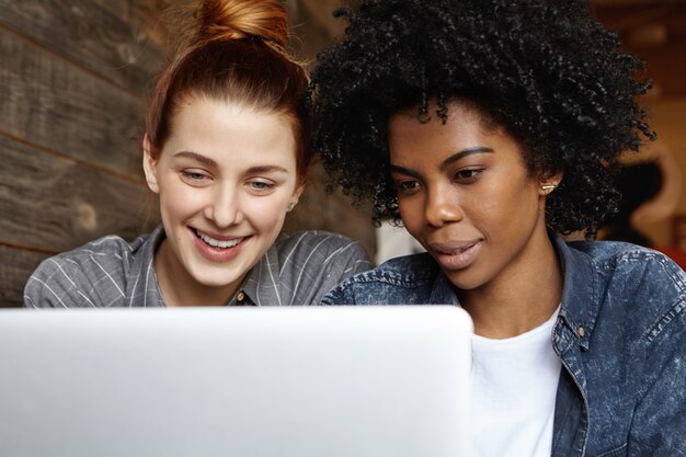 Coppie lesbiche femminili interrazziali omosessuali felici che godono del wi-fi gratuito