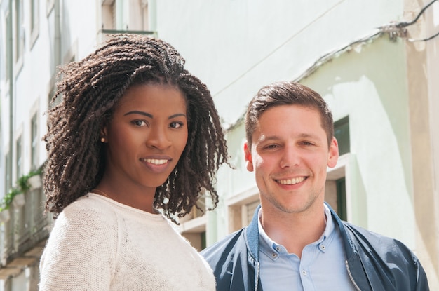 Coppie multiculturali felici che propongono all&#39;aperto