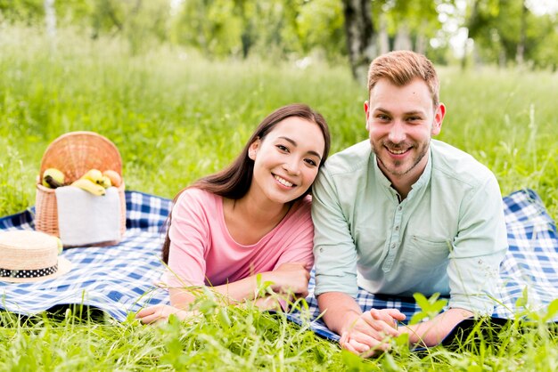 Coppie multirazziali sorridenti che posano sul picnic