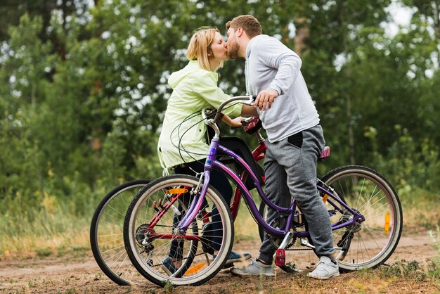 Coppie oblique che baciano sulle biciclette