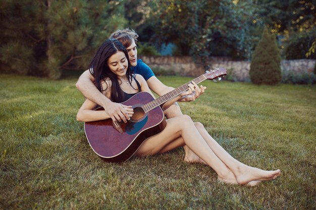 Coppie romantiche che si siedono sull'erba nel giardino