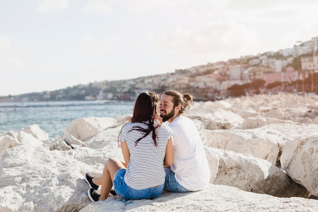 Coppie romantiche che si siedono sulle rocce al mare