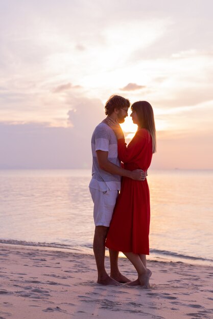 Coppie romantiche felici sulla spiaggia tropicale al tramonto.