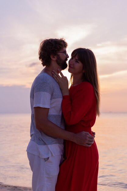 Coppie romantiche felici sulla spiaggia tropicale al tramonto.