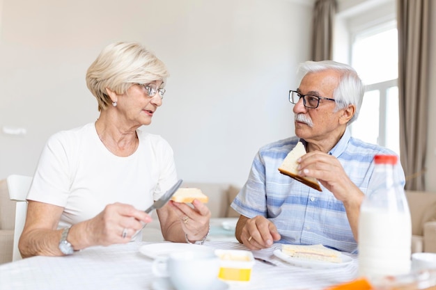 Coppie senior allegre che mangiano colazione a casa