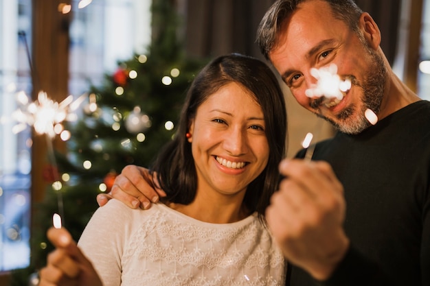 Coppie senior allegre vicino all'albero di Natale con le luci