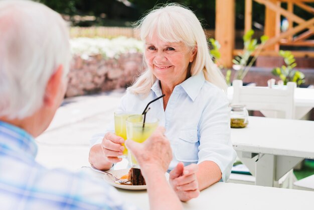 Coppie senior che bevono il succo di arancia sulla veranda all'aperto