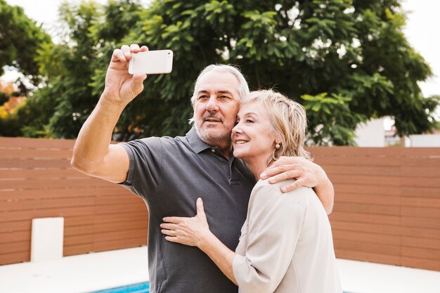 Coppie senior che prendono selfie in giardino